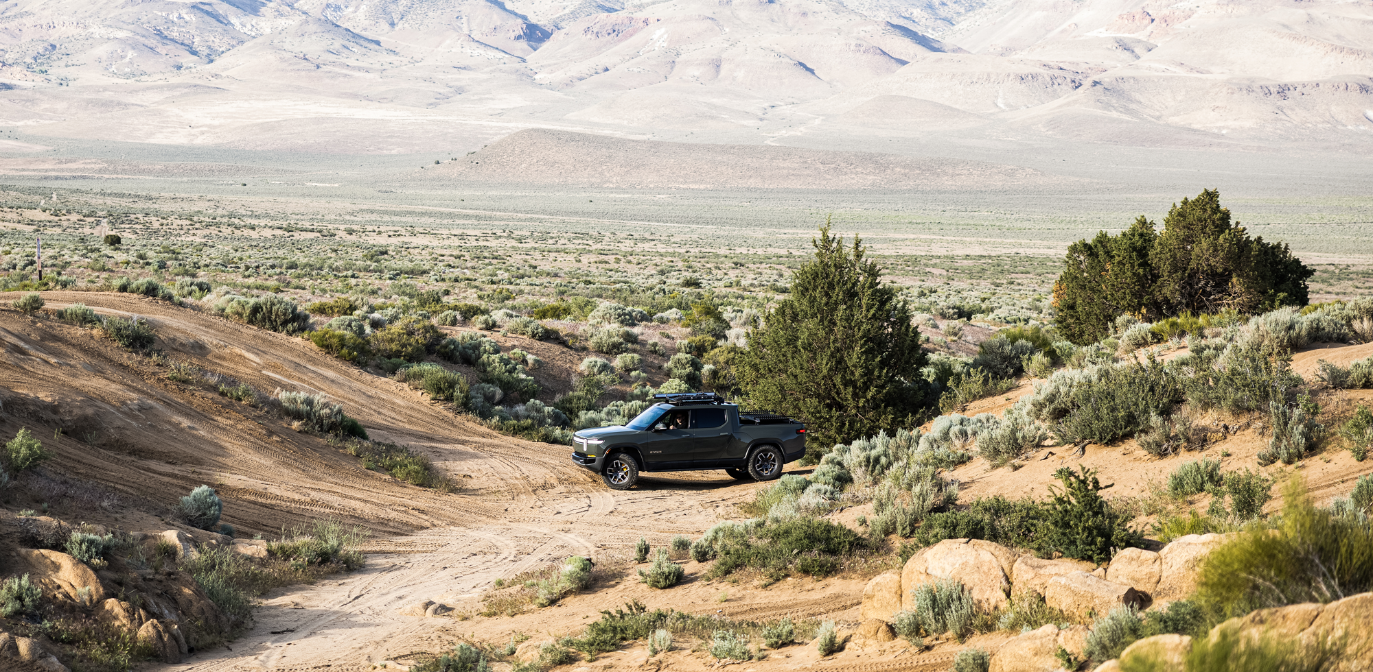 Overland Nomadic products displayed on a Rivian vehicle, including roof racks and off-road gear